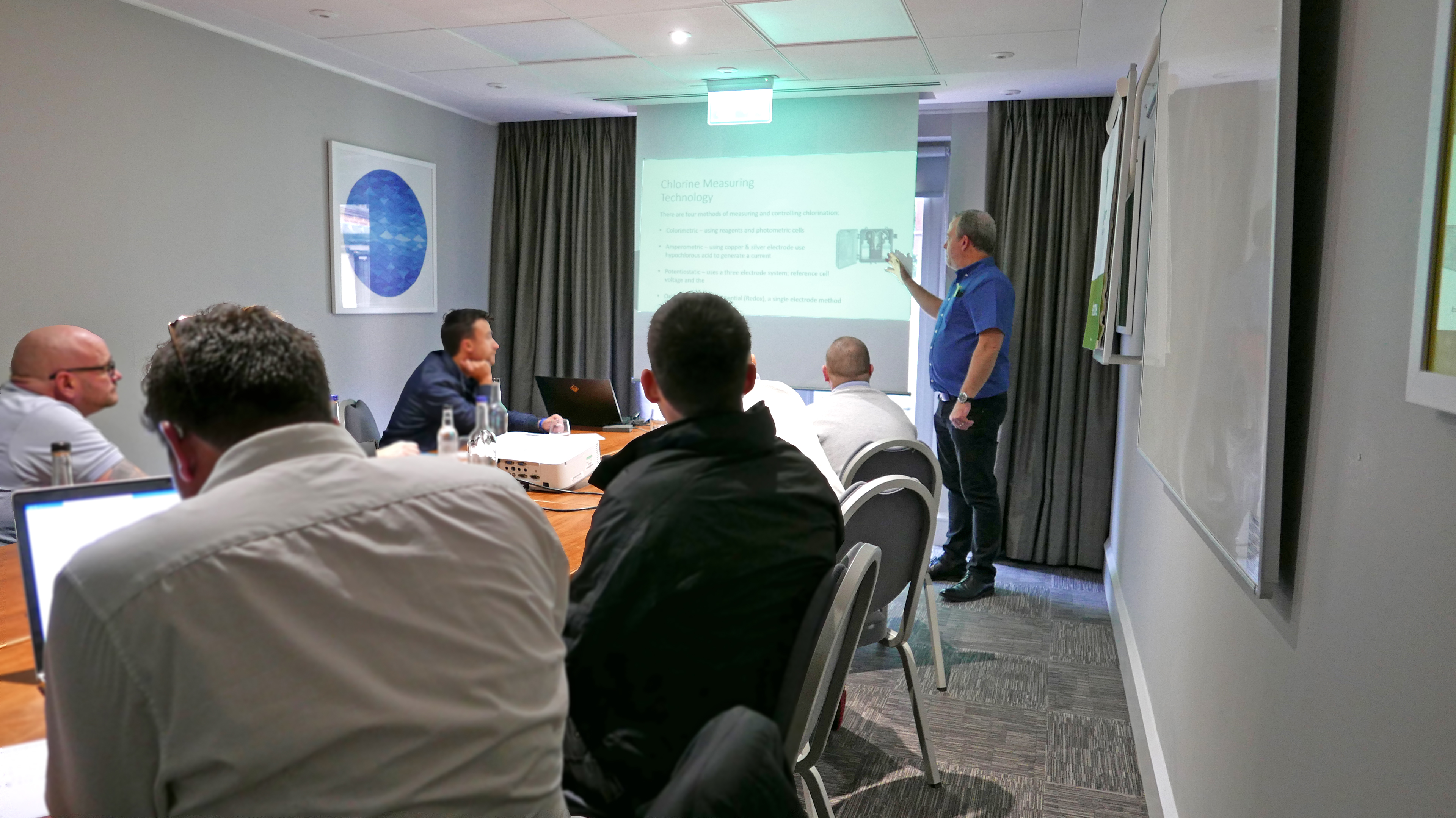 A photo of a group of trainees in a conference room with their tutor